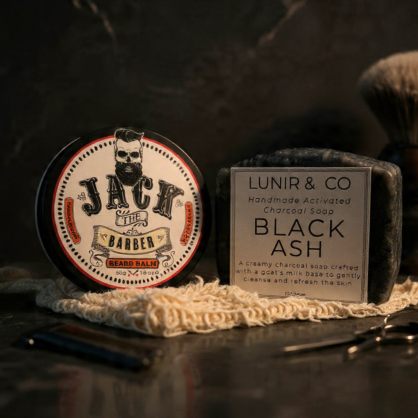 Barber products including a jar of 'Jack the Barber' bear balm and a bar of 'Lunir & Co' black ash soap on a dark background.