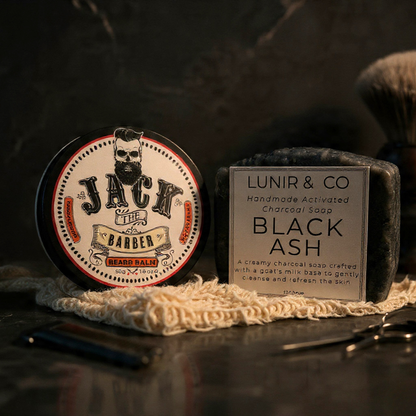 Barber products including a jar of 'Jack the Barber' bear balm and a bar of 'Lunir & Co' black ash soap on a dark background.