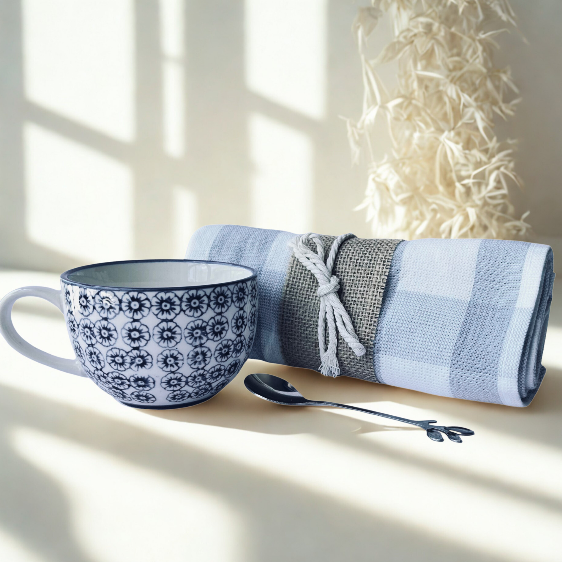 Blue and white patterned mug with a spoon and folded towel on a light surface.