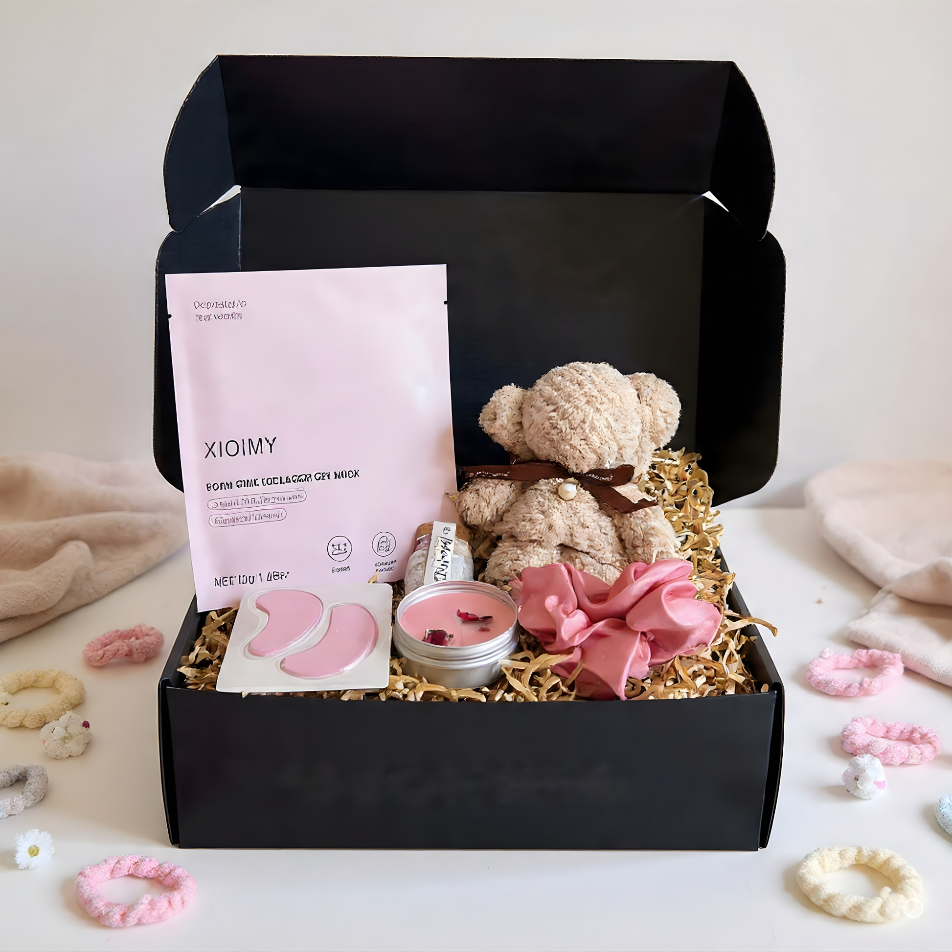 Gift box with teddy bear, candle, and other items on a white background