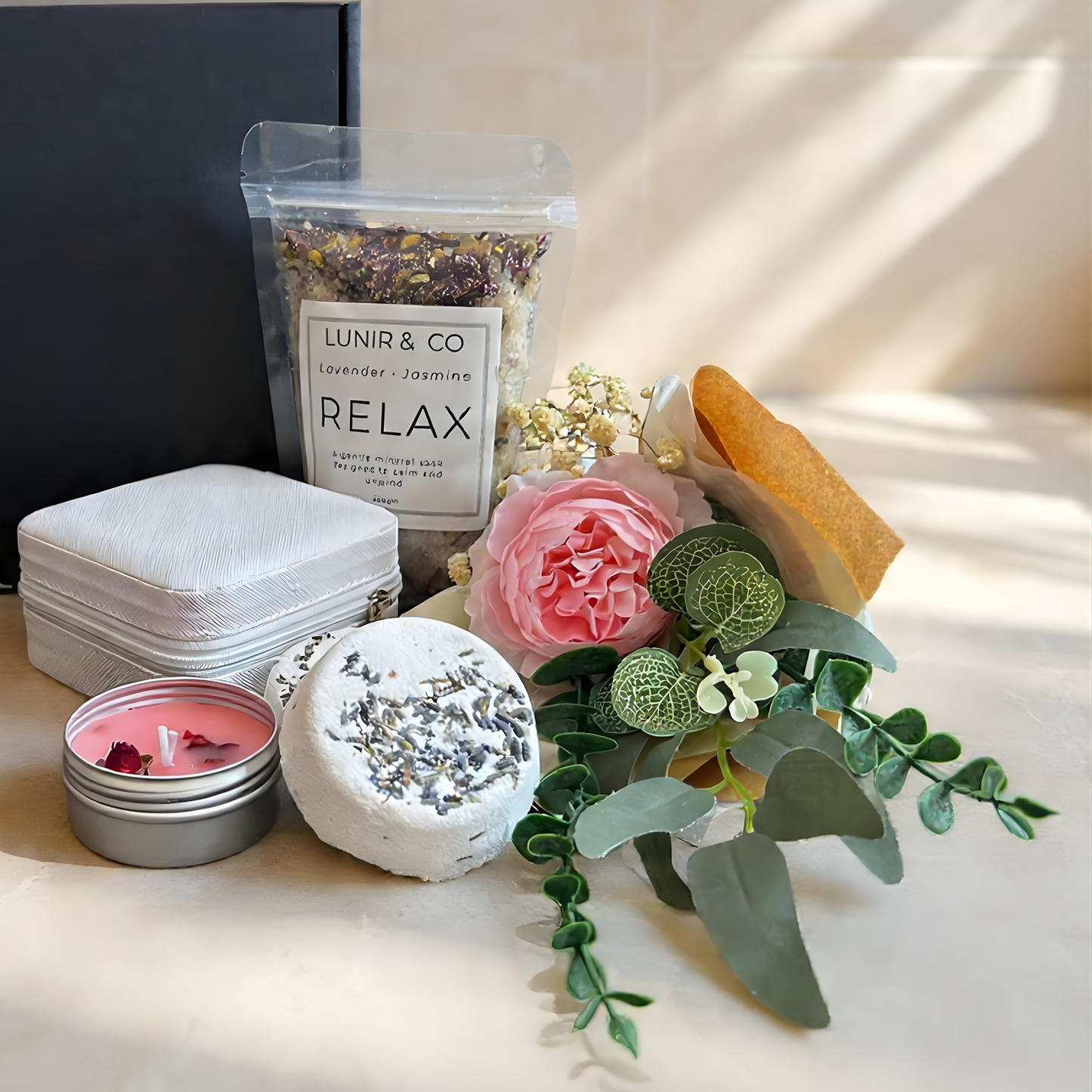 Gift box with teddy bear, candle, and other items on a light background