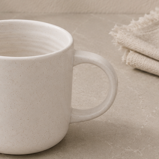 White ceramic mug on a beige surface with folded fabric in the background