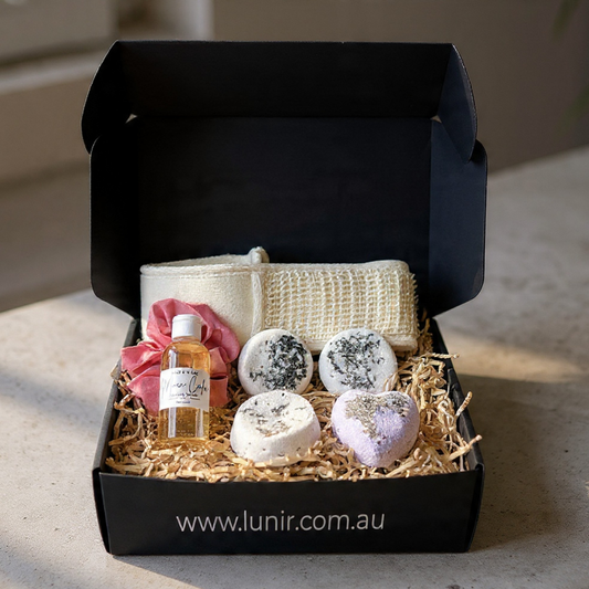 Gift set with bath bombs, soap, and a bottle in a black box on a neutral background