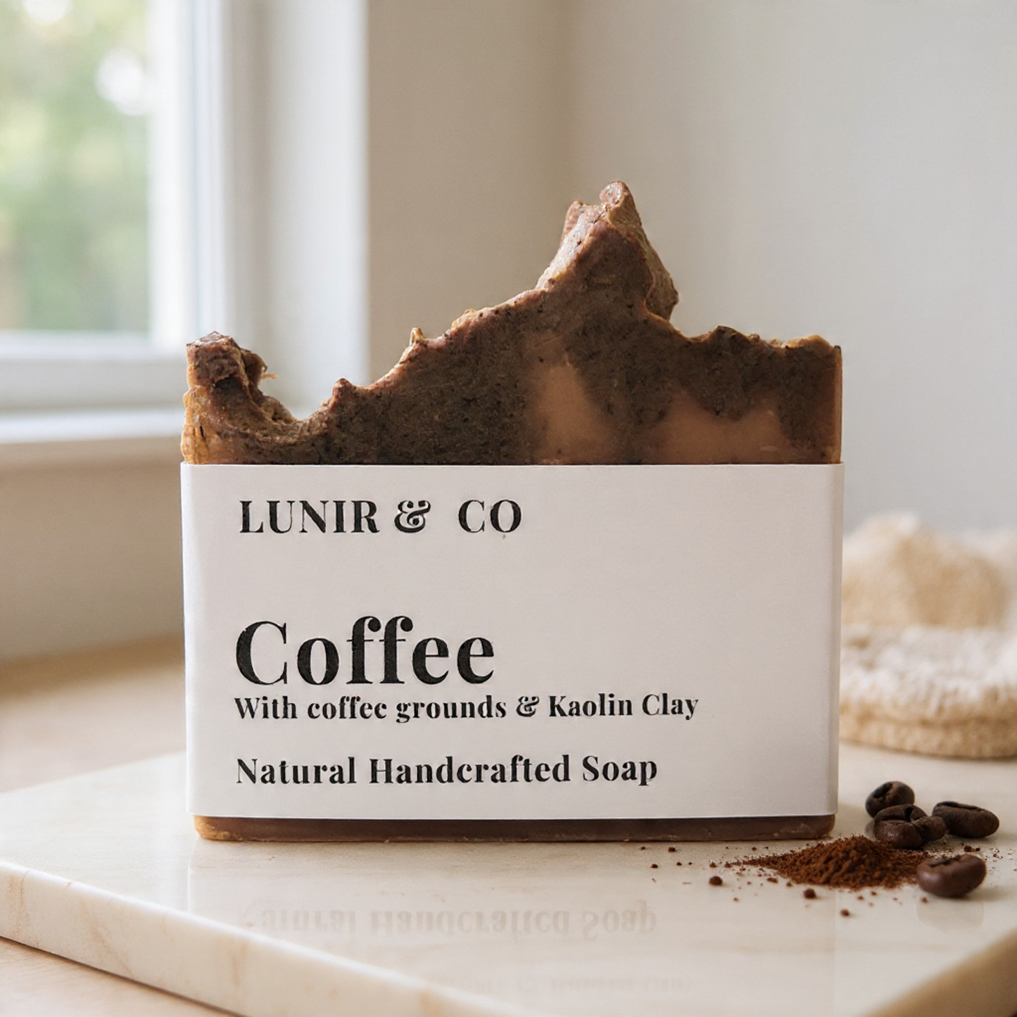 Bar of coffee soap with visible branding on a marble surface