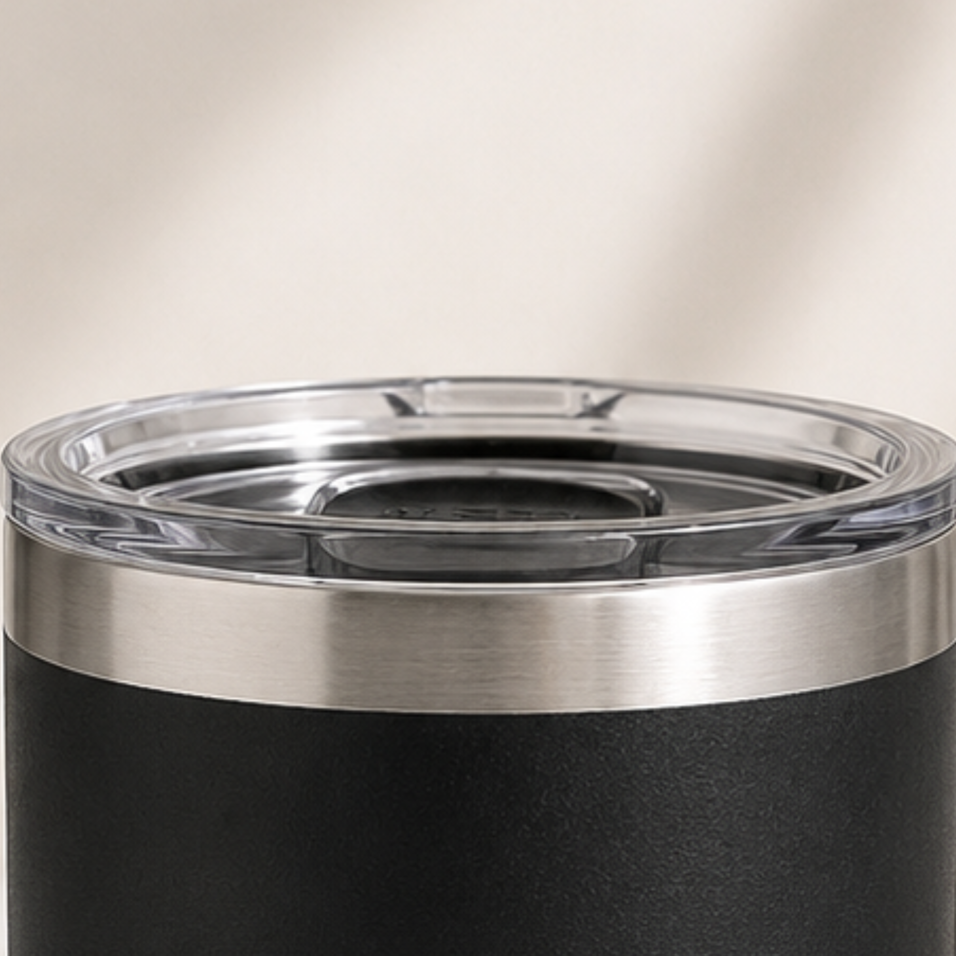 Close-up of a black tumbler with a silver lid on a neutral background