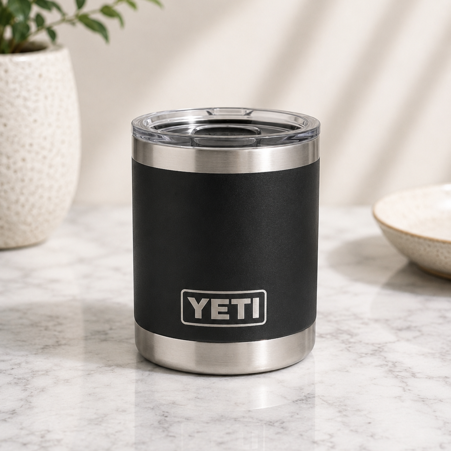 Black YETI tumbler on a marble surface with a plant and bowl in the background