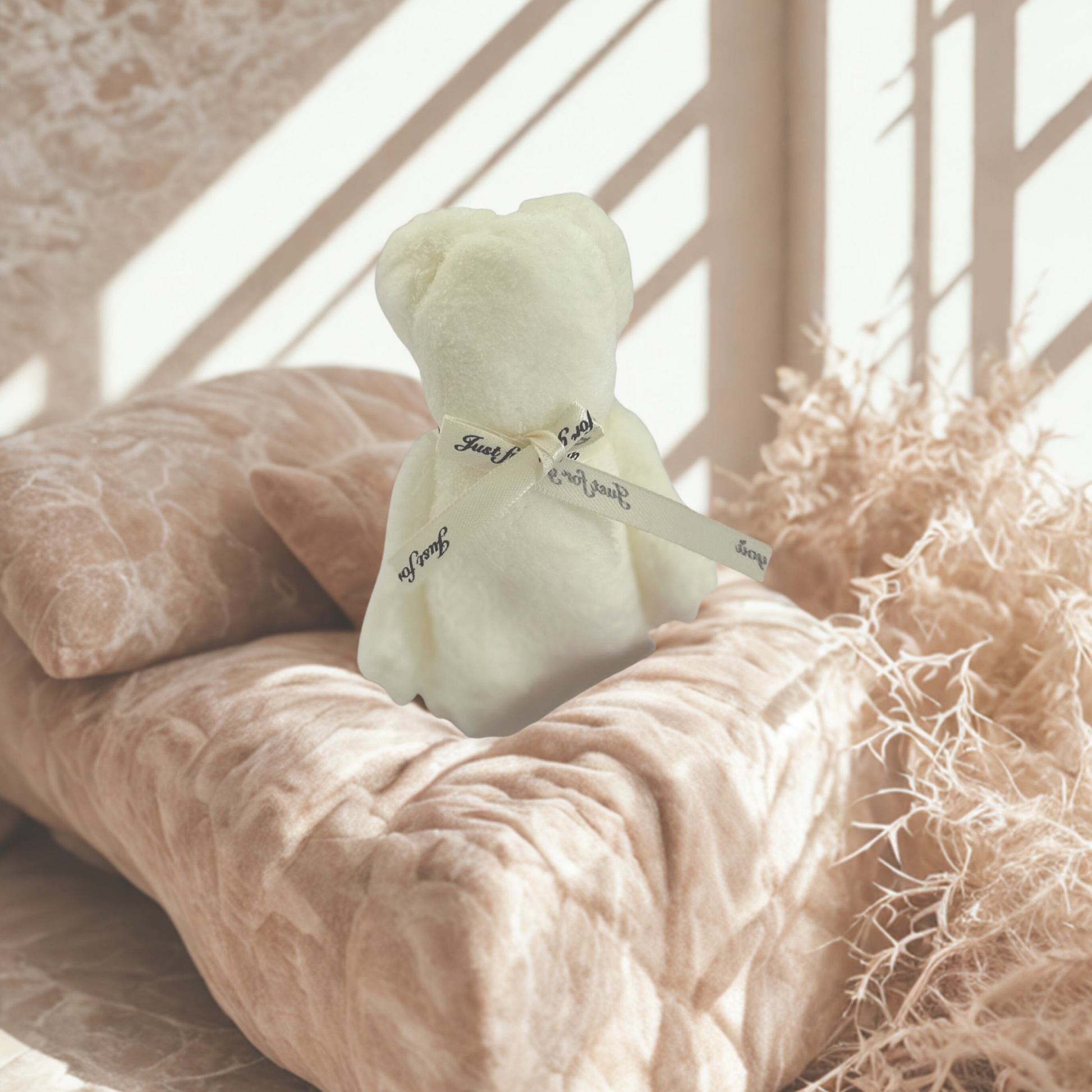 Small light green teddy bear with a bow on a textured surface