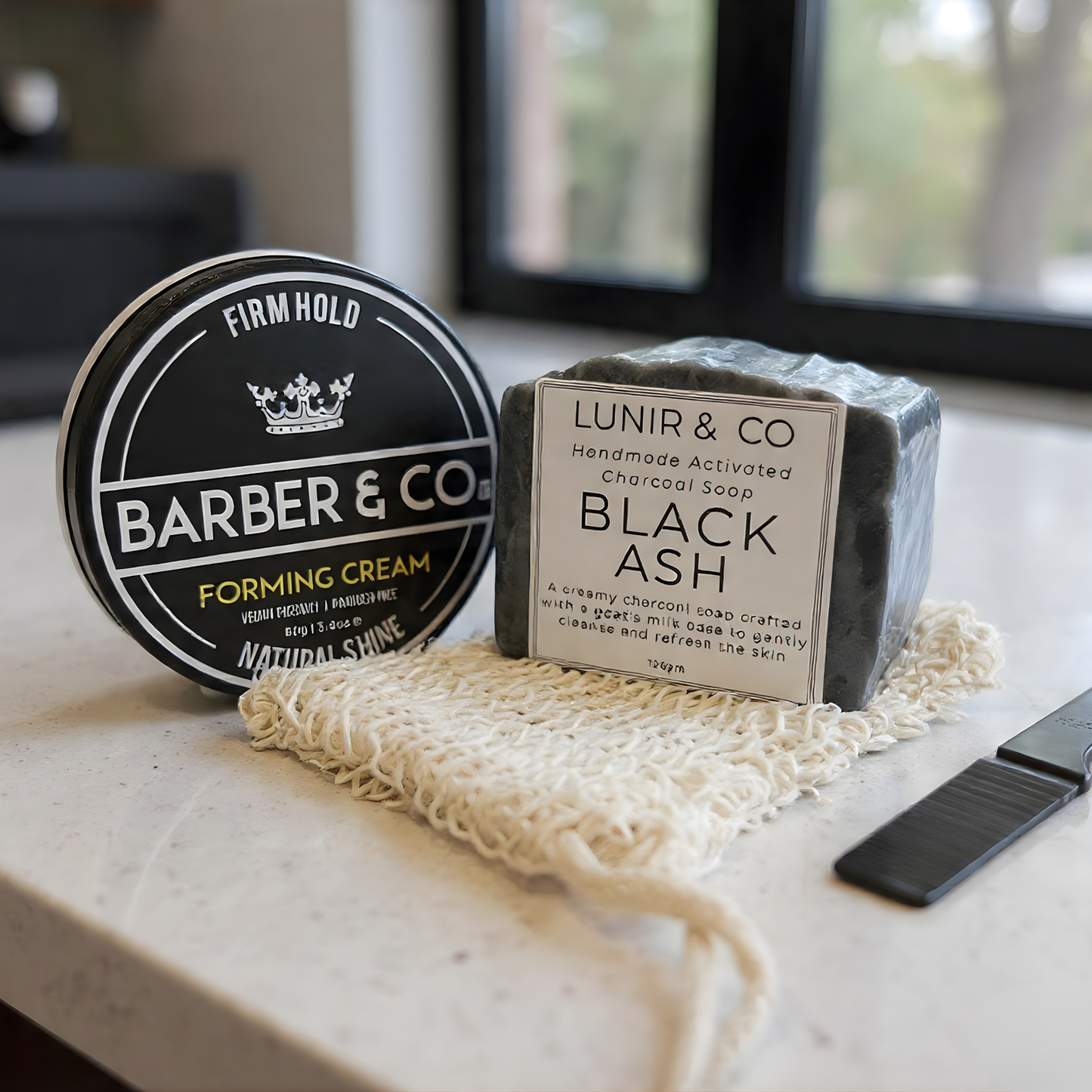 Men's grooming products including an after-shave balm, deodorant stick, and pomade in a branded box on a marble surface.