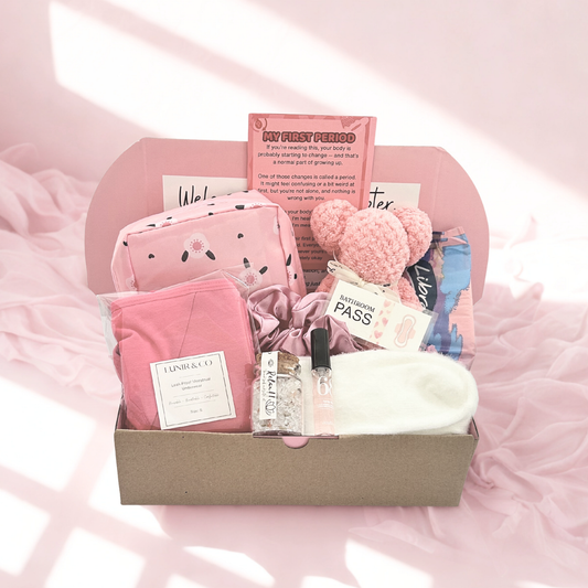 Gift basket with bath products including a candle, soap, and bath bombs on a white surface.
